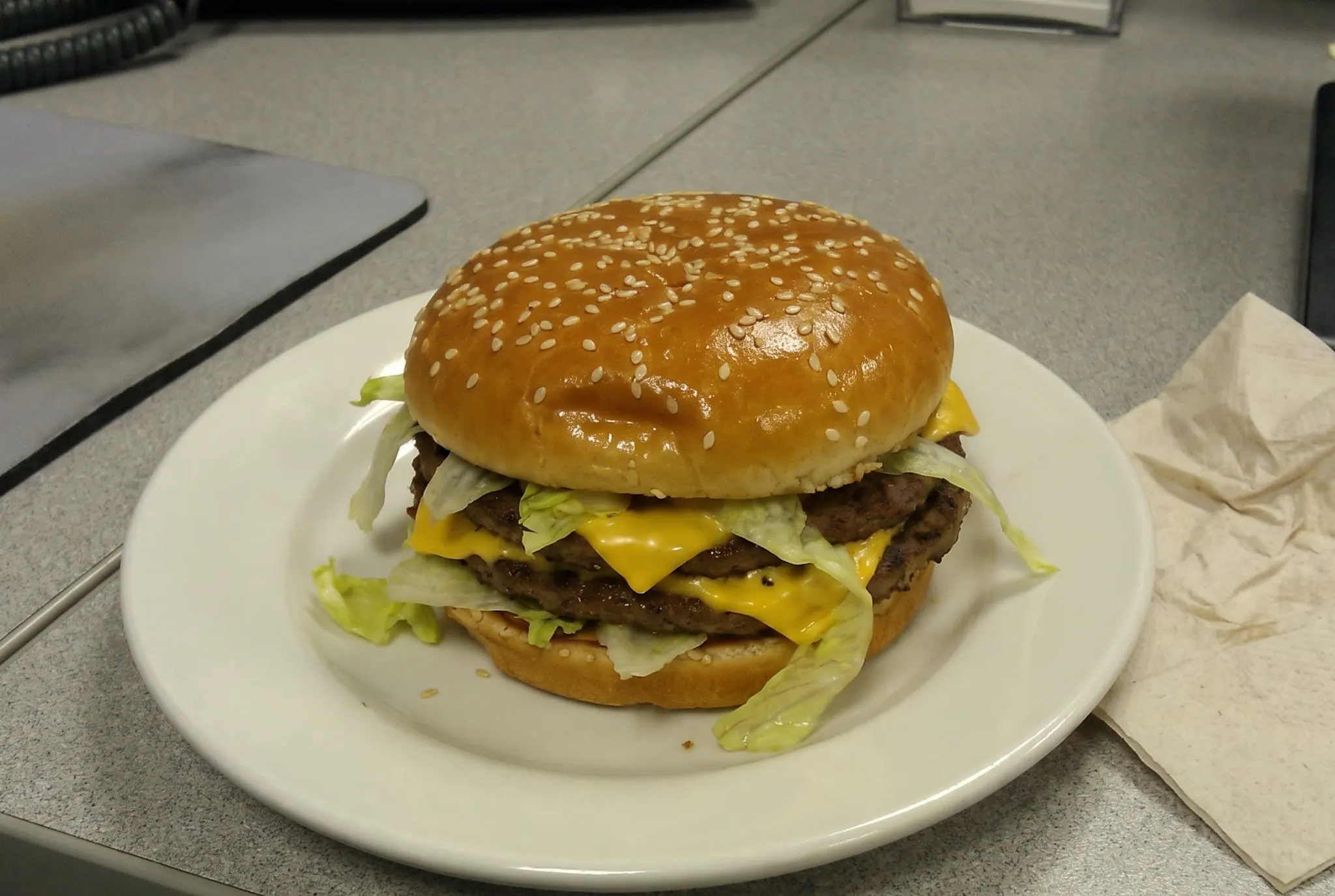 Cheeseburger on a plate on an office desk, shot on a phone