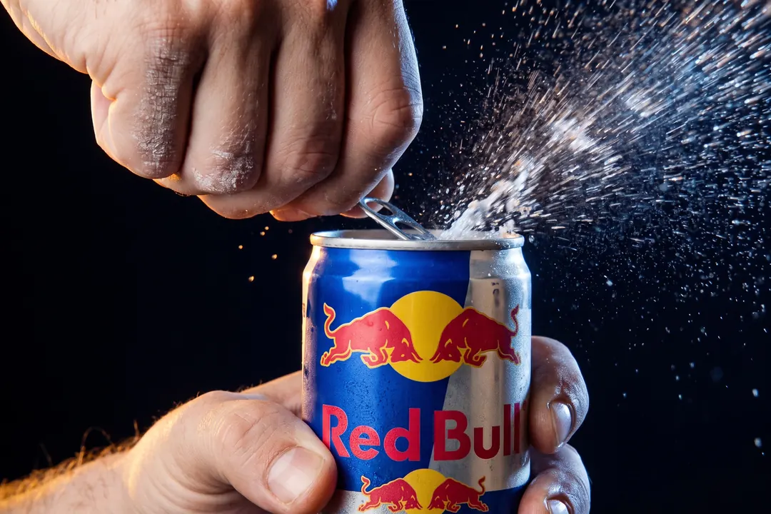 Hand cracking open a cold can in a burst of spray