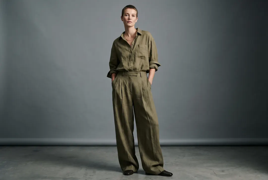 Model in an olive utility jumpsuit against a grey backdrop